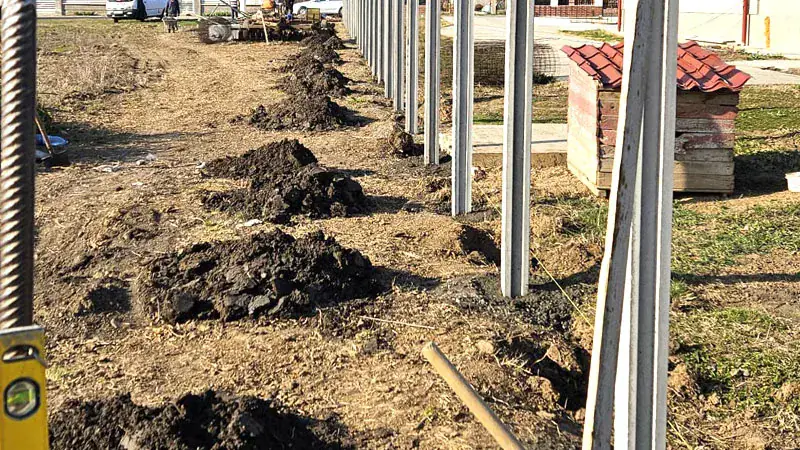 Výkopy a betonové sloupky během montáže plotu